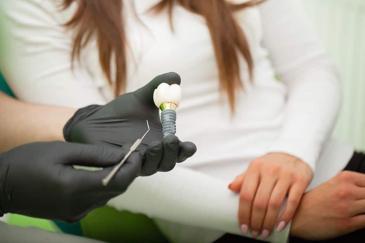 Dentist showing a dental implant model to a patient.