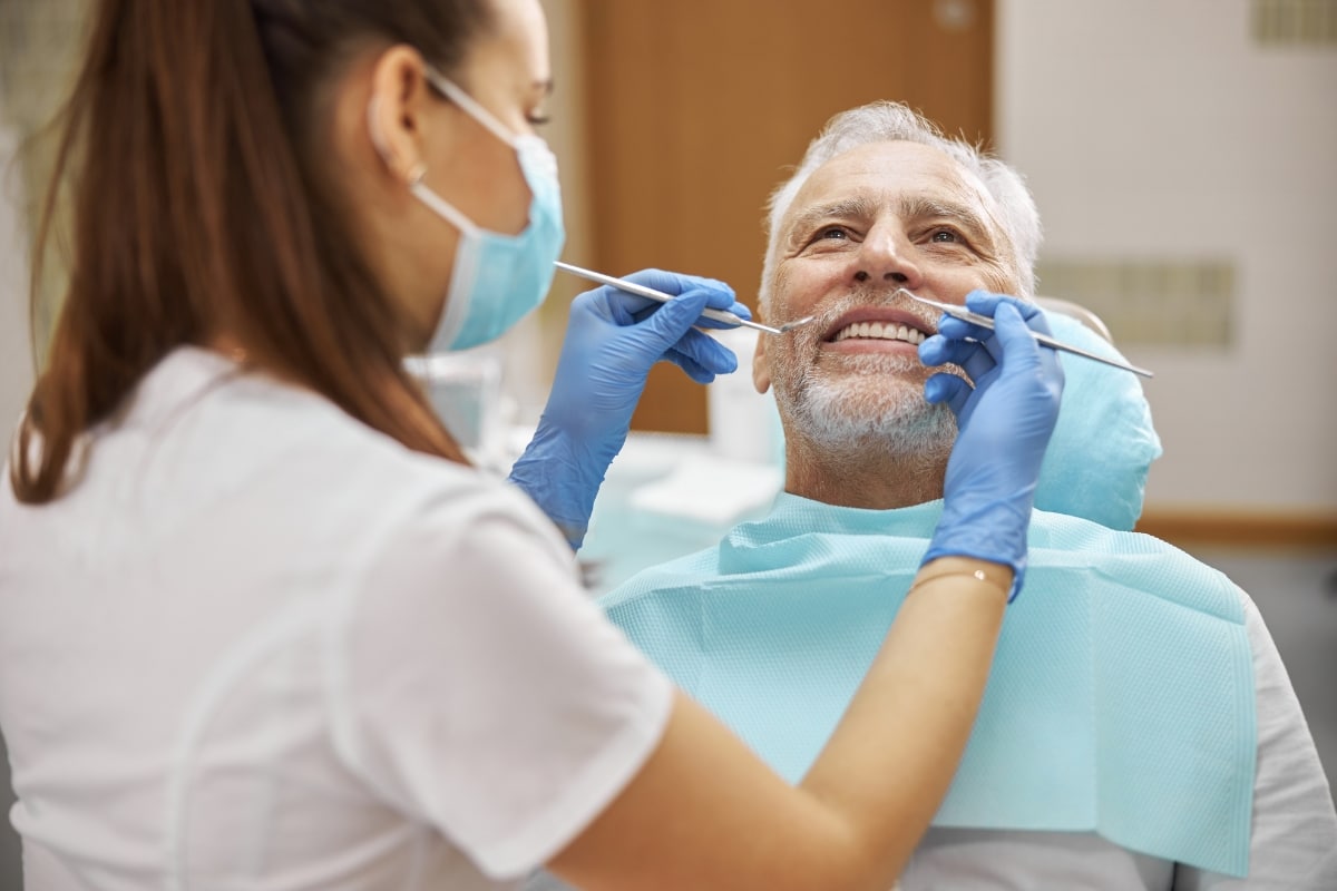 Dentist examining smiling older adult patient during routine dental check-up