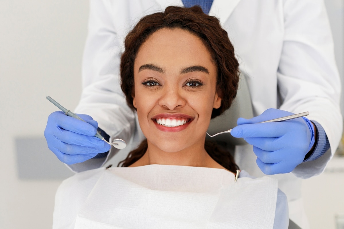 Smiling woman at dentist with tools for tooth sensitivity examination